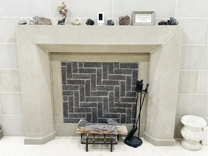 Carved limestone fireplace mantel with herringbone firebox