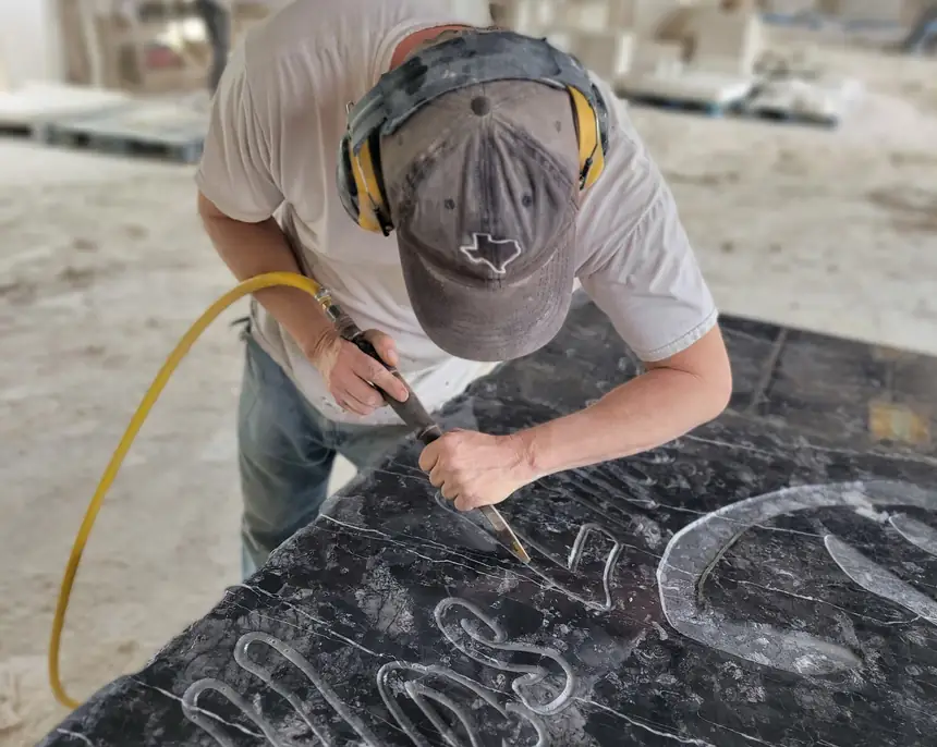 Stone carver lettering a slab by hand in the Mesquite shop